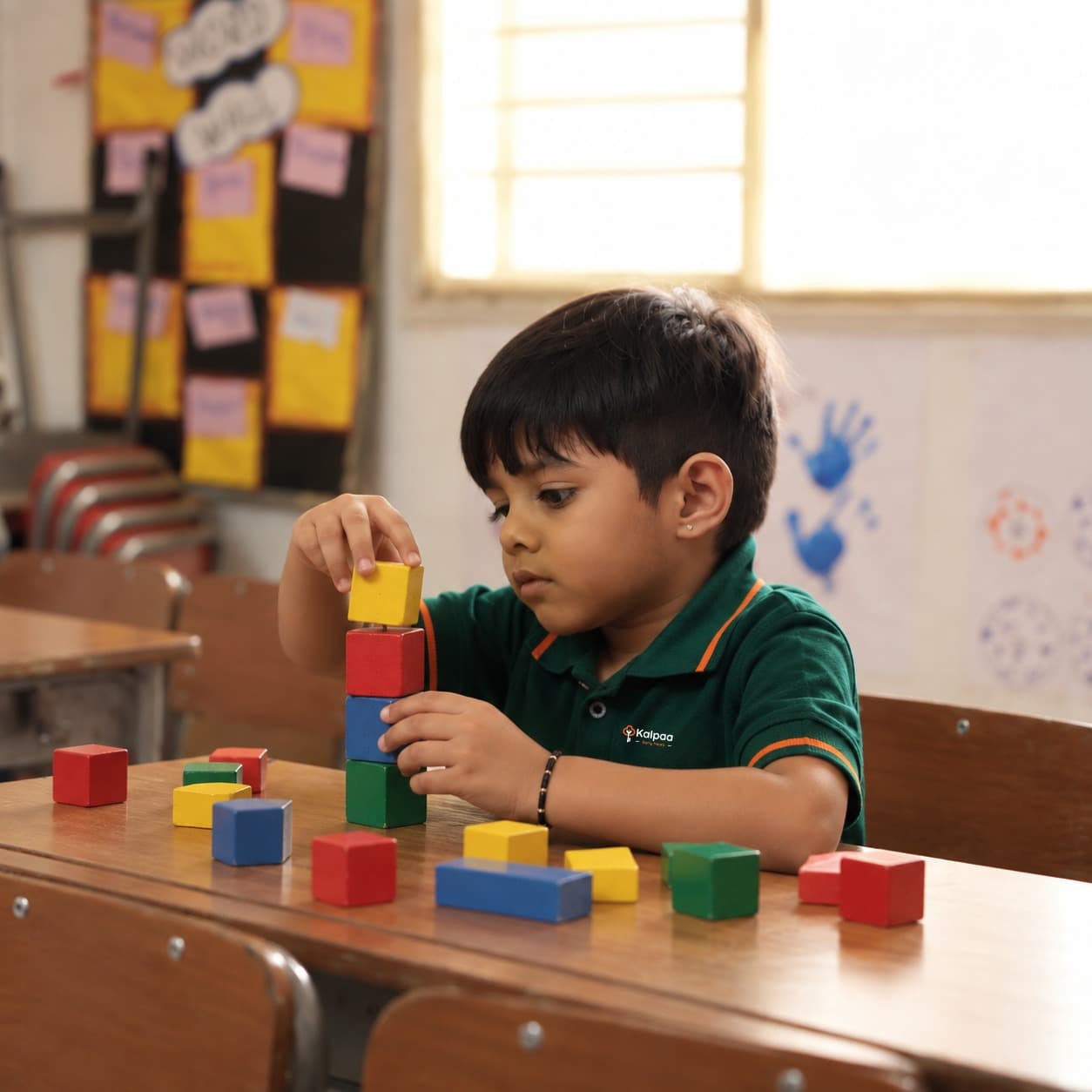 A Kalpaa boy stacking coloured wooden blocks at his desk